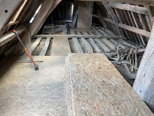 Un chantier de construction montrant des murs en parpaings de béton gris, des portes intérieures, des câbles électriques apparents et des outils sur un sol en béton.
