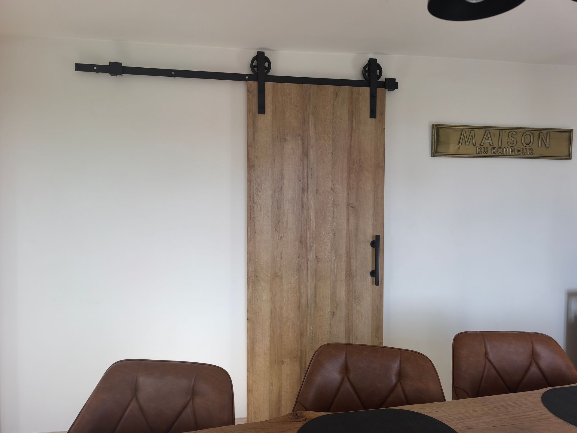 Dans un chantier de construction, des panneaux de plaques de plâtre blanc sont installés sur une isolation en mousse jaune fixée sur des montants métalliques.