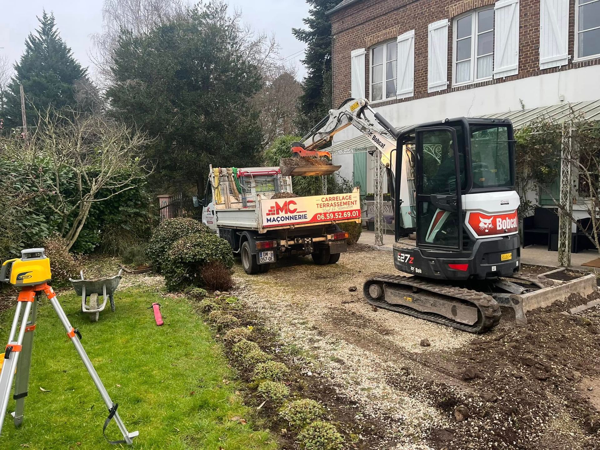 Sur un chantier, un ouvrier portant un gant vert vif place un bloc de béton gris sur un mur recouvert de mortier.
