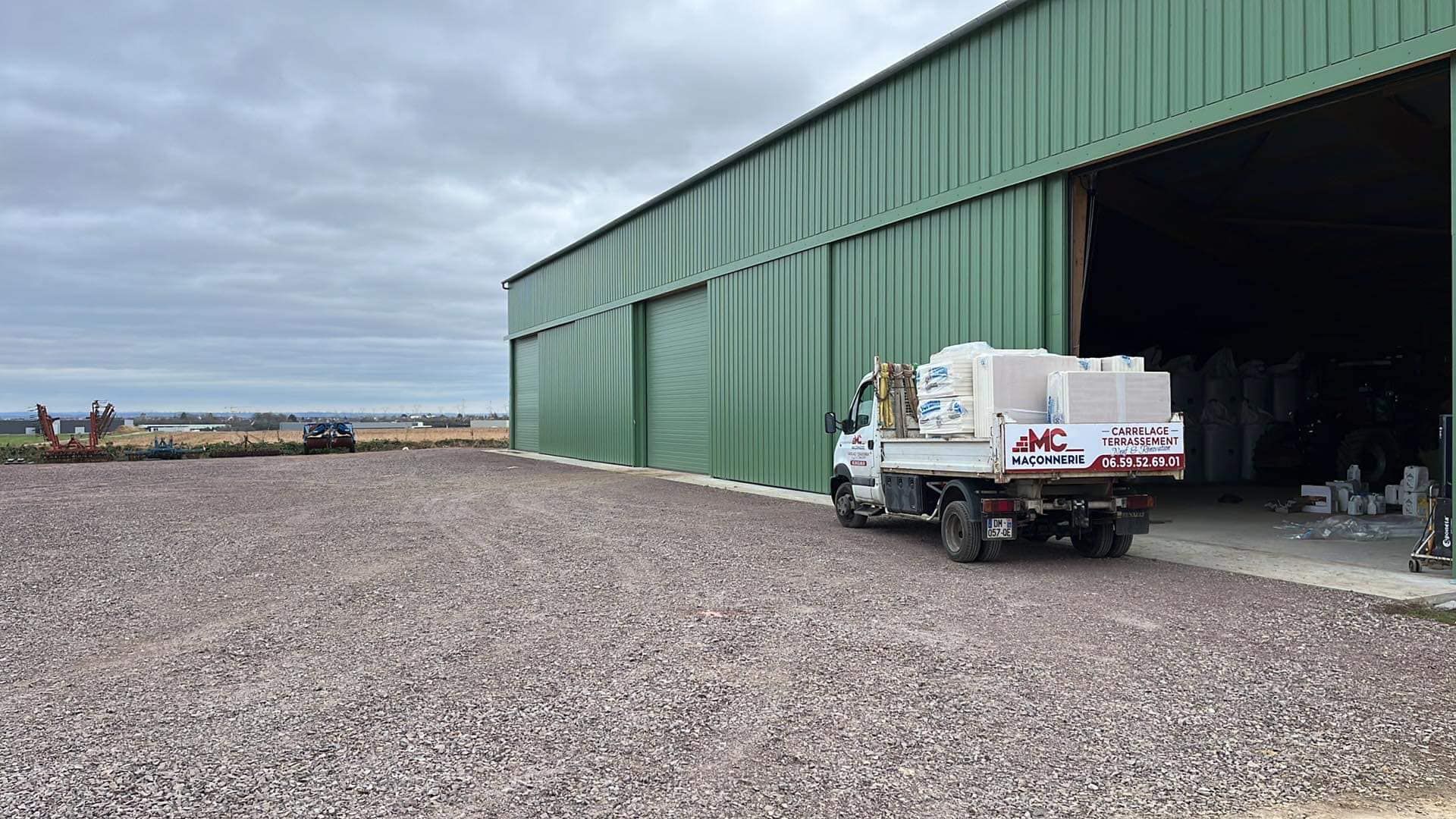 Une personne installe des carreaux de sol rectangulaires foncés sur une sous-couche à quadrillage, à l'aide d'un cutter et d'un mètre ruban.
