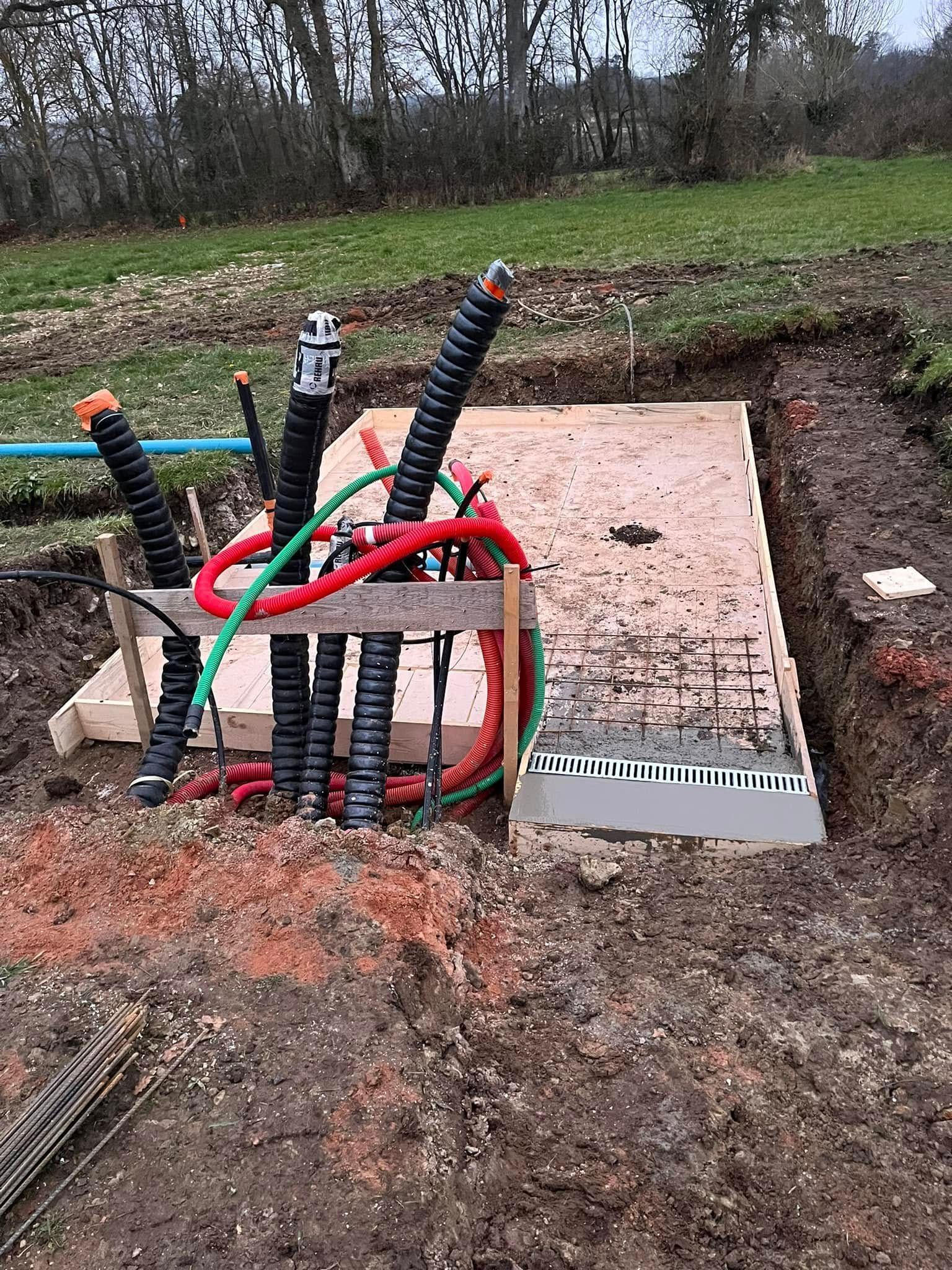 Sur un chantier de construction, une main gantée utilise une truelle pour appliquer du mortier sur une rangée de briques en terre cuite orange.