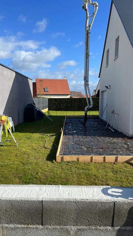 Un ouvrier ganté utilise une truelle métallique pour étaler du mortier entre des briques orange sur un chantier de construction.