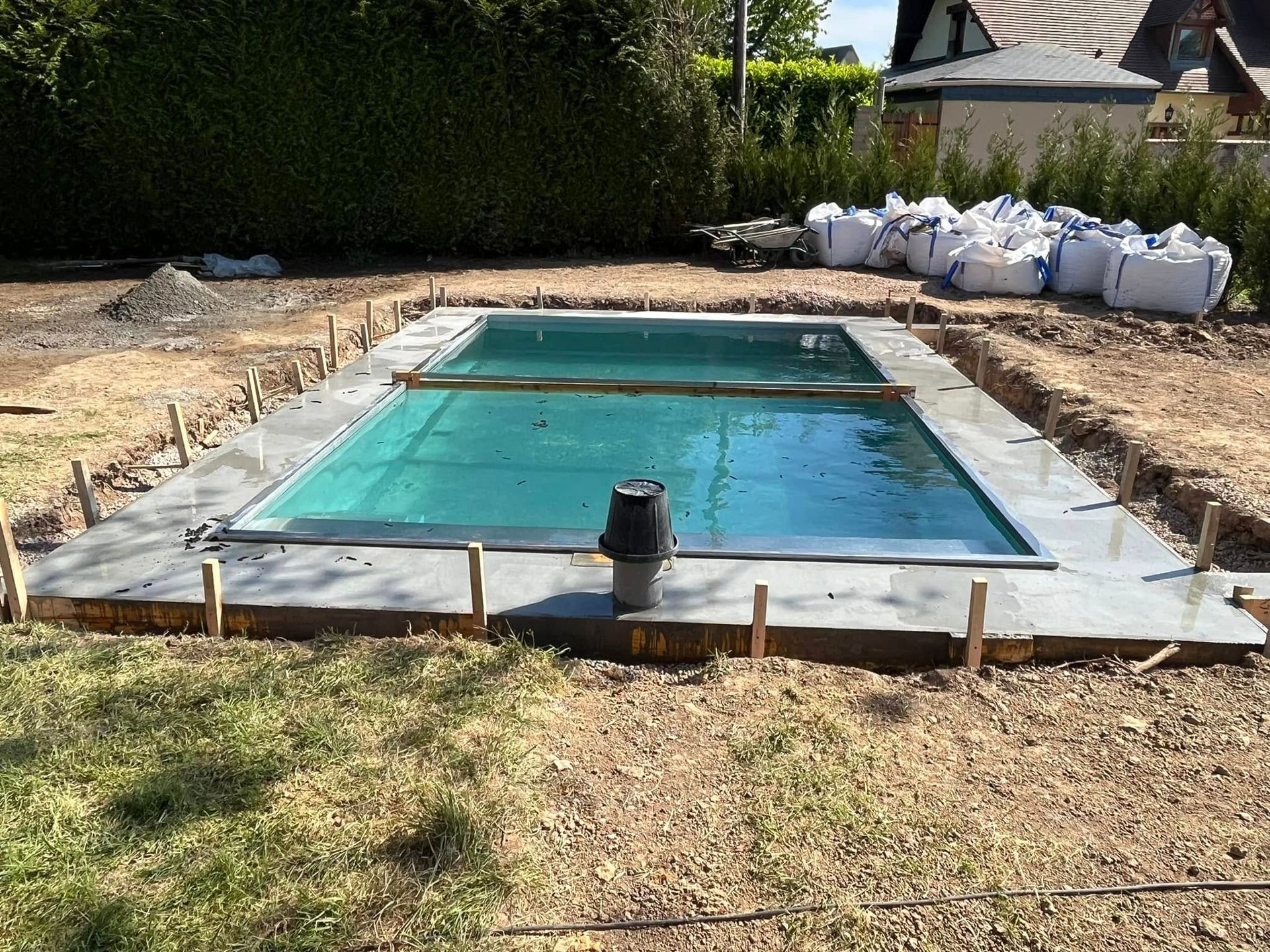 Un abri de piscine télescopique aux cadres sombres et panneaux translucides, posé sur une terrasse en pierre.