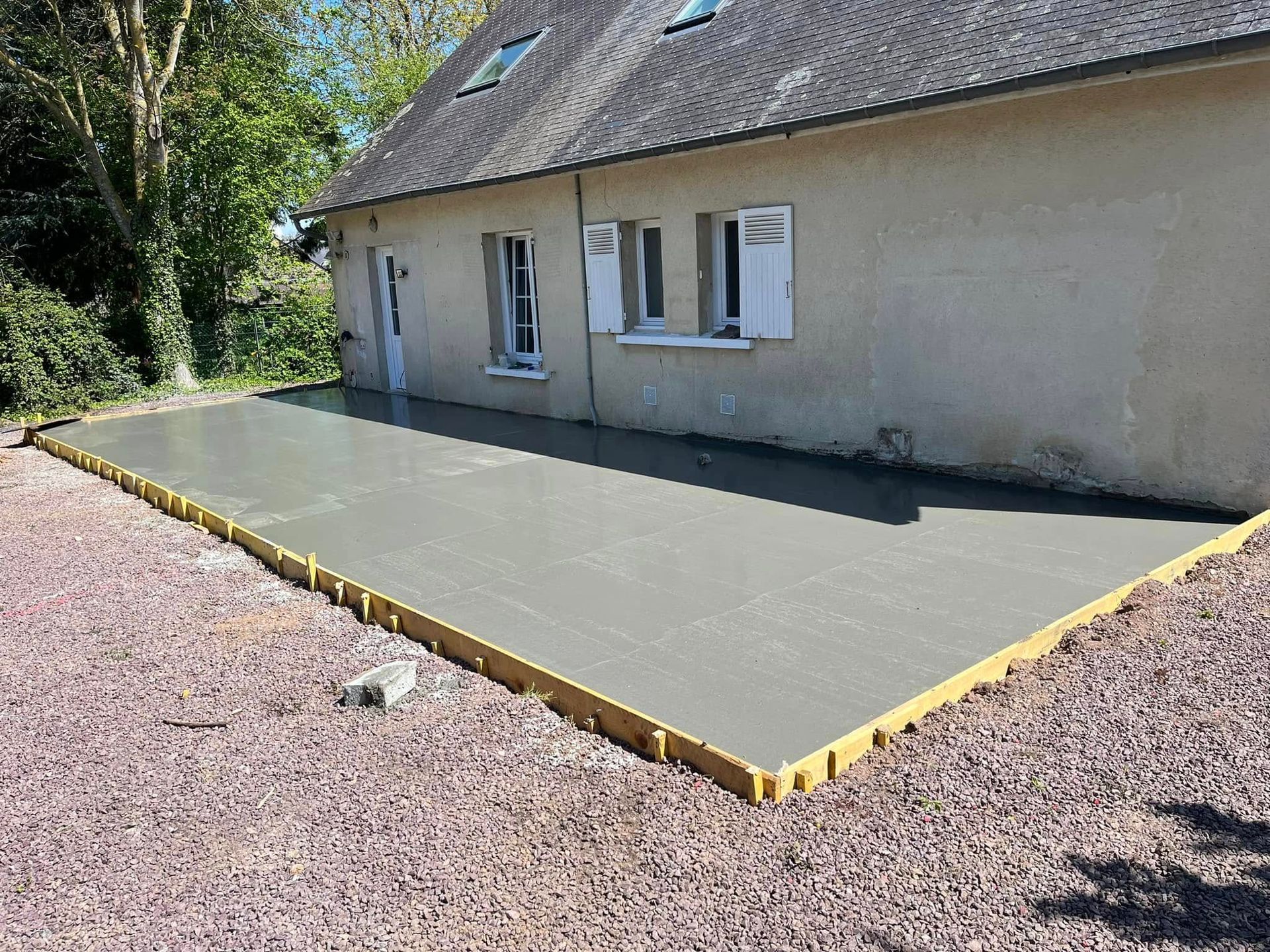 Portail double en aluminium gris foncé et portillon latéral pour piétons installés entre deux piliers en stuc clair.