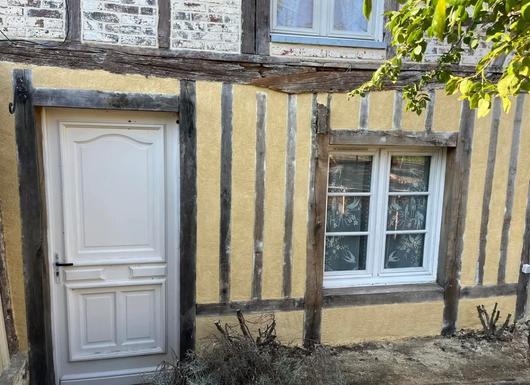 Une personne posant des briques d'argile rouge avec du mortier à l'aide d'une truelle métallique sur un chantier de construction.