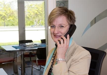 Eine Frau sitzt an einem Schreibtisch und telefoniert.