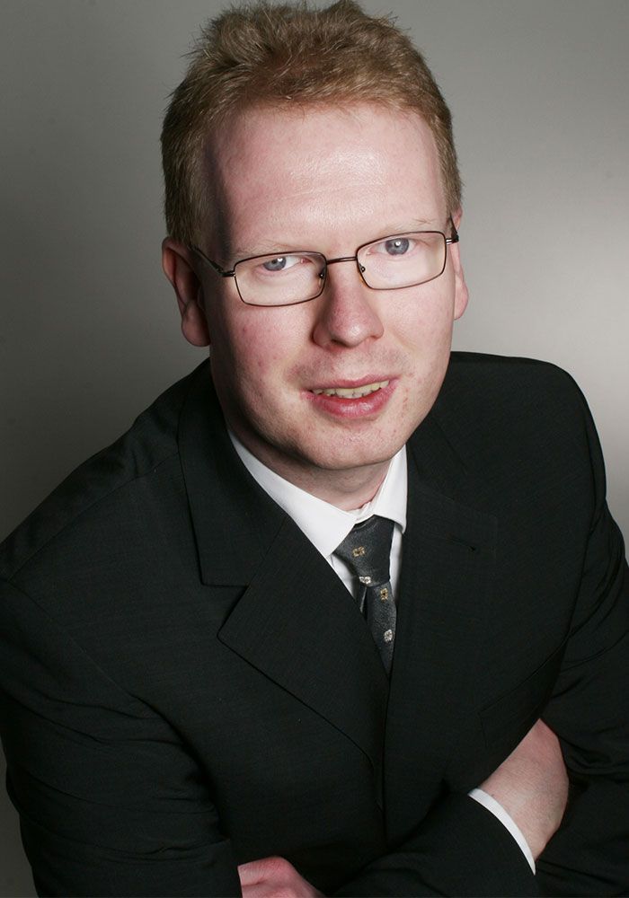 Ein Mann in Anzug und Krawatte mit verschränkten Armen