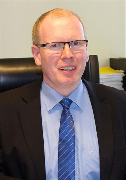 Ein Mann in Anzug und Krawatte lächelt in die Kamera