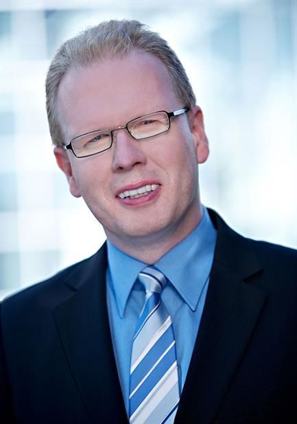 Ein Mann in Anzug und Krawatte lächelt in die Kamera