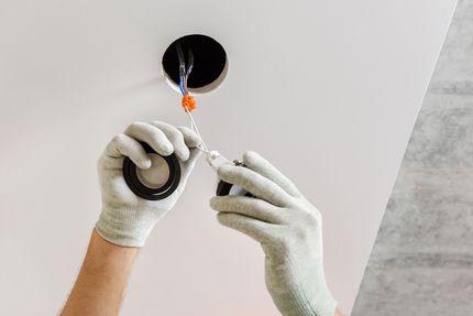 Une personne installe un luminaire dans un plafond.