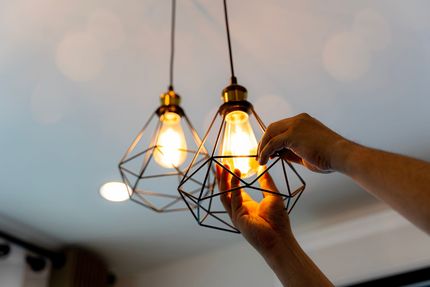 Une personne change une ampoule dans une suspension.