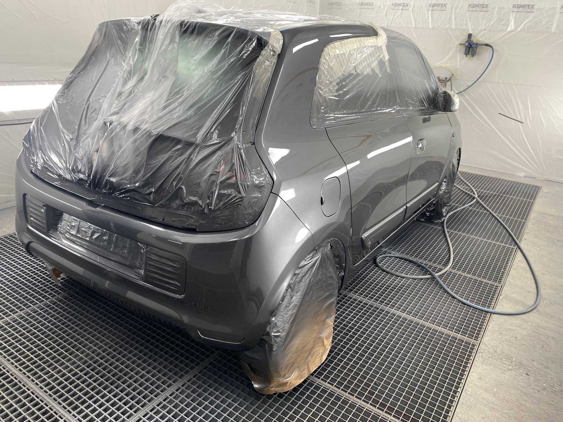 Voiture grise vue de l'arrière sous plastique pour être peinte