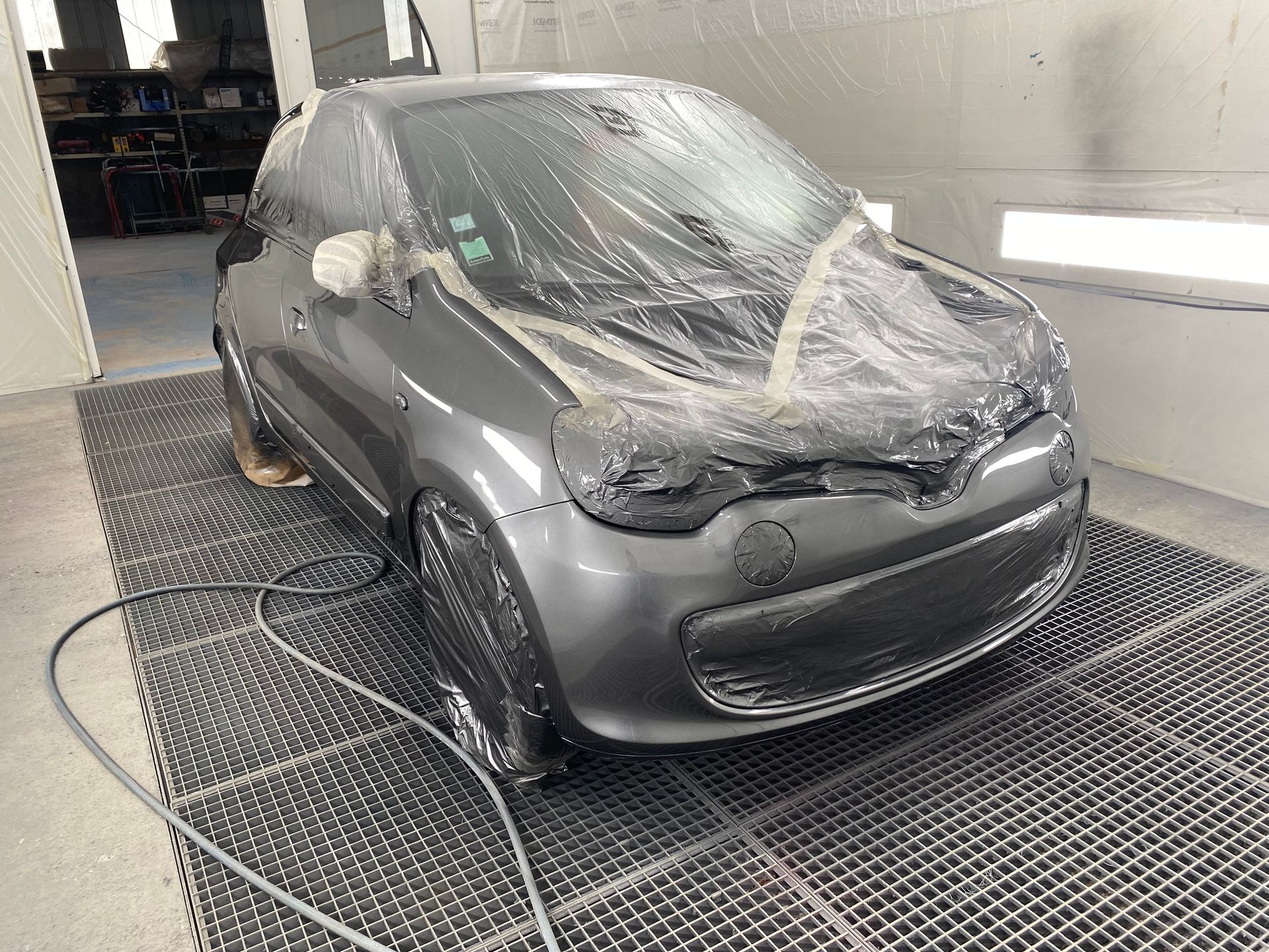 Voiture grise de profil sous plastique pour être peinte