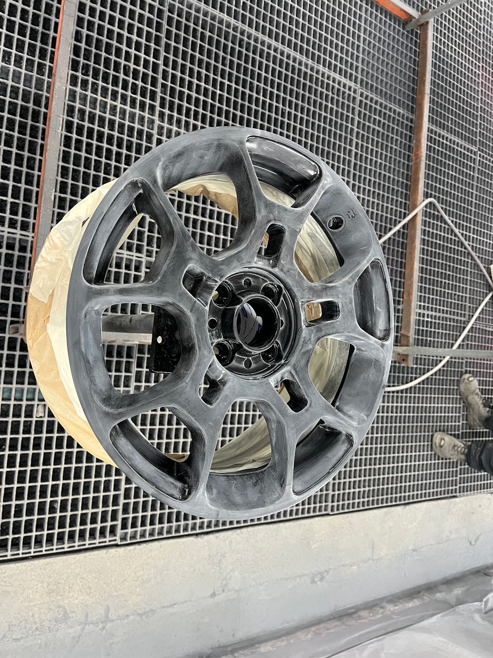 Grande roue métallique fixée à un mur en treillis métallique dans un environnement industriel.