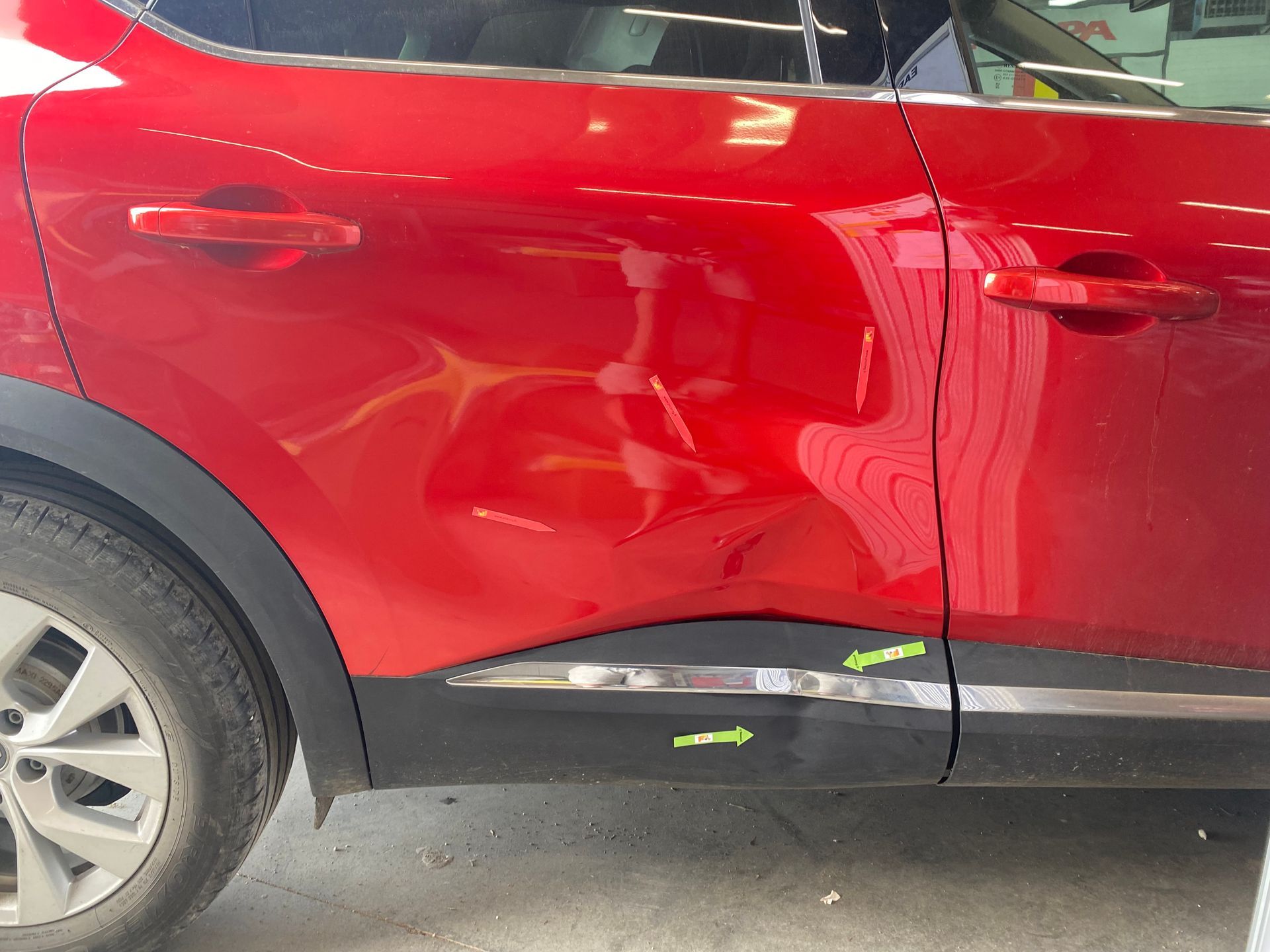 Voiture rouge de profil avec des impacts sur la carrosserie