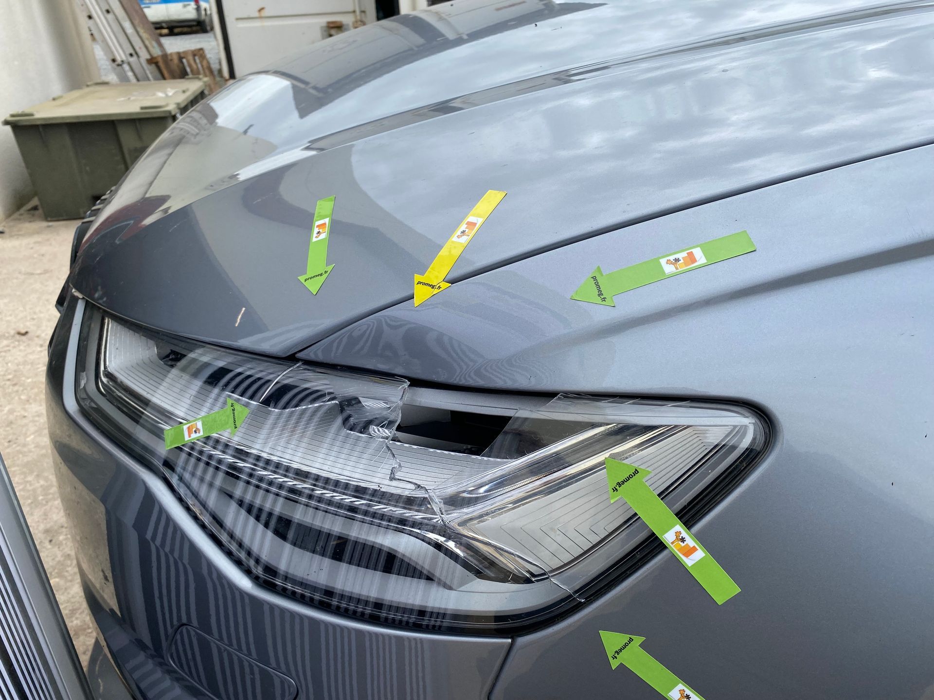 Voiture grise marquée par des flèches autour d'un phare avant cassé