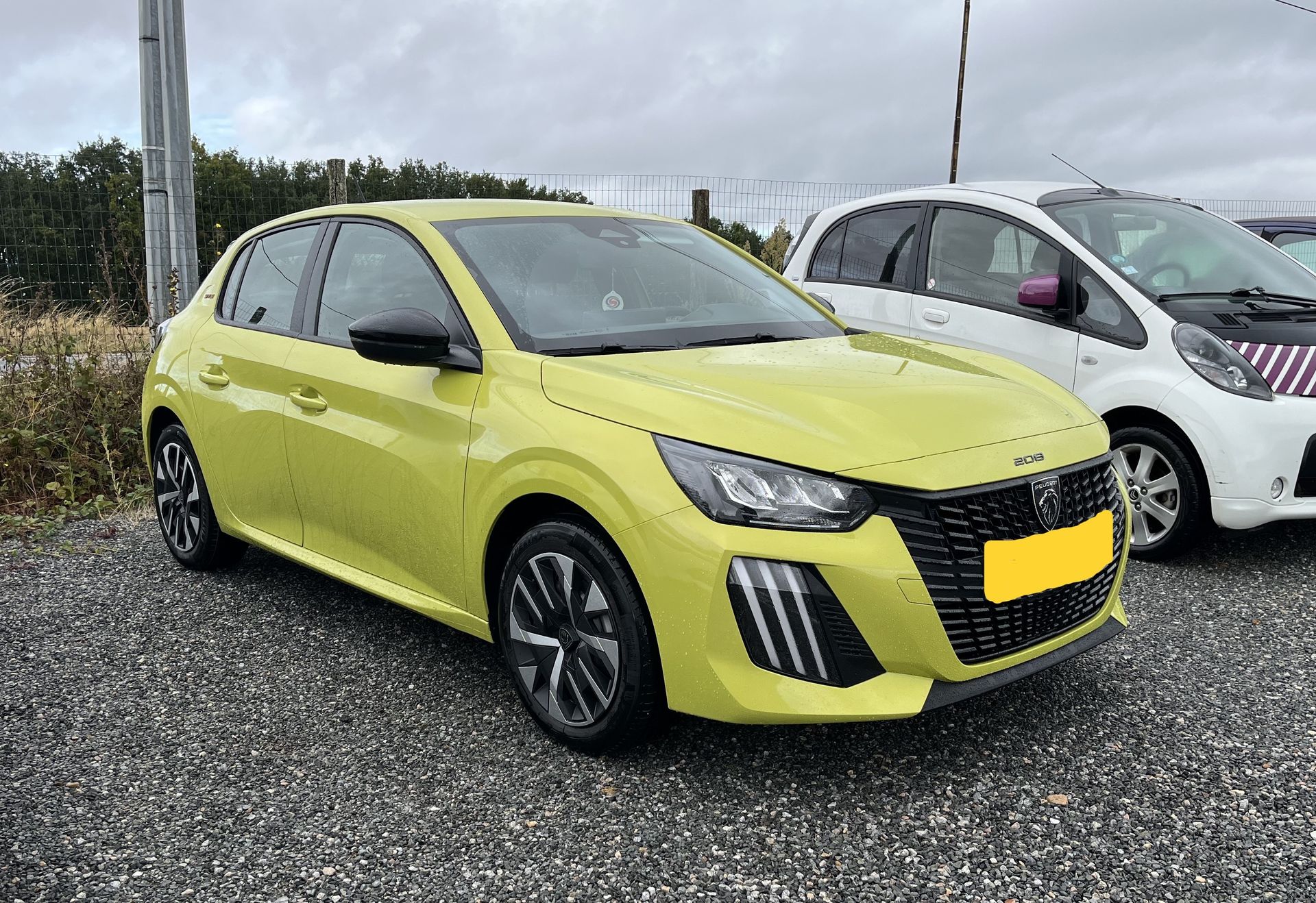 Une voiture jaune à hayon dont la plaque d’immatriculation est floutée.