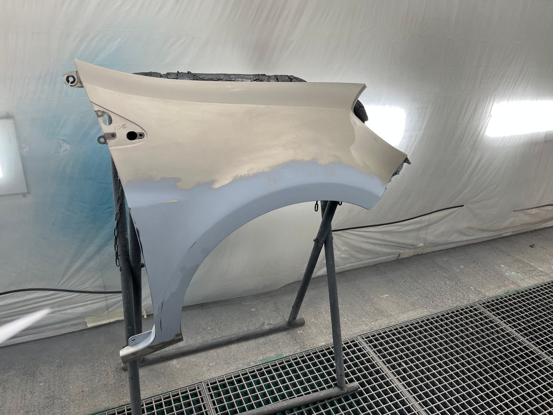 Grand panneau métallique sur un support, dans une cabine de peinture industrielle