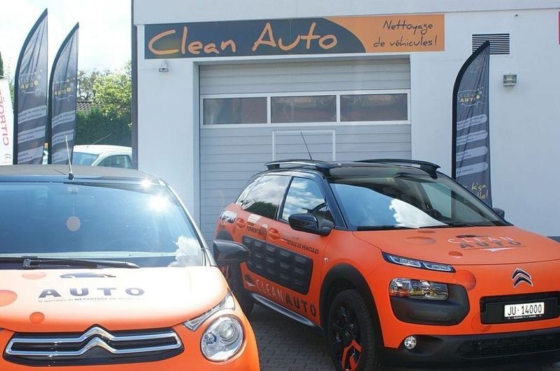 Deux voitures sont garées devant un magasin de voitures propres