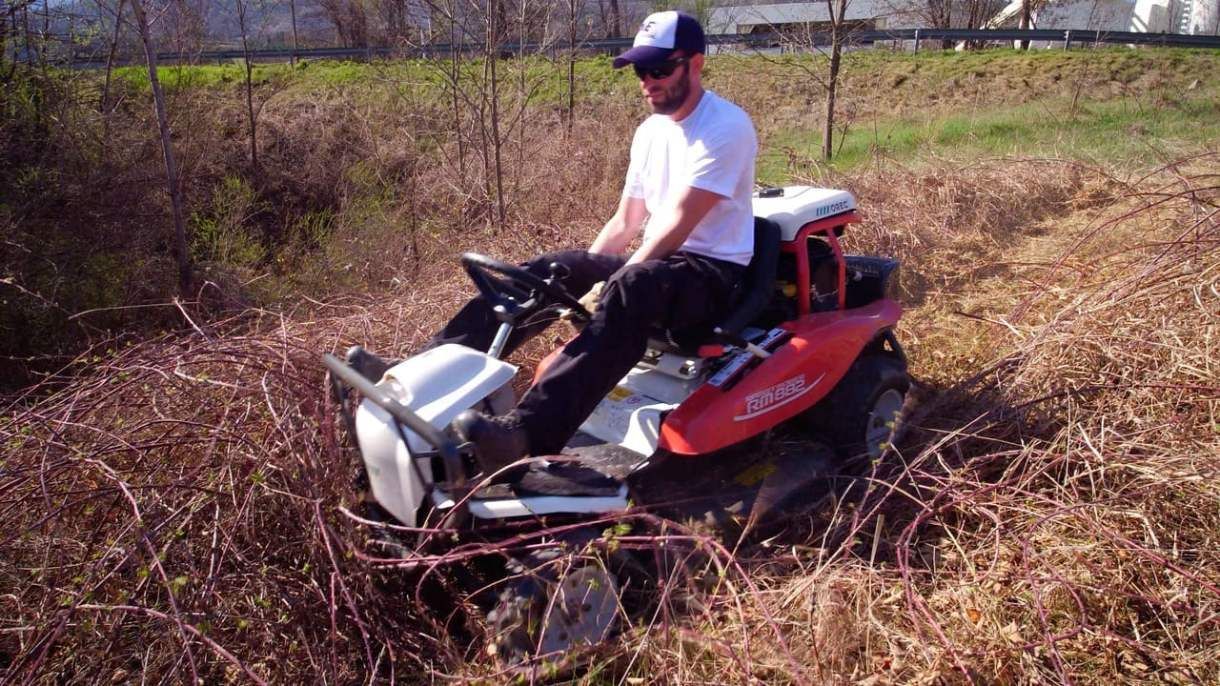 Un homme passe la tondeuse dans un tas de broussaille