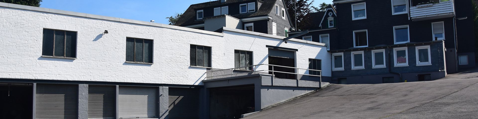 Ein weißes Gebäude mit vielen Fenstern steht neben einem schwarzen Gebäude.