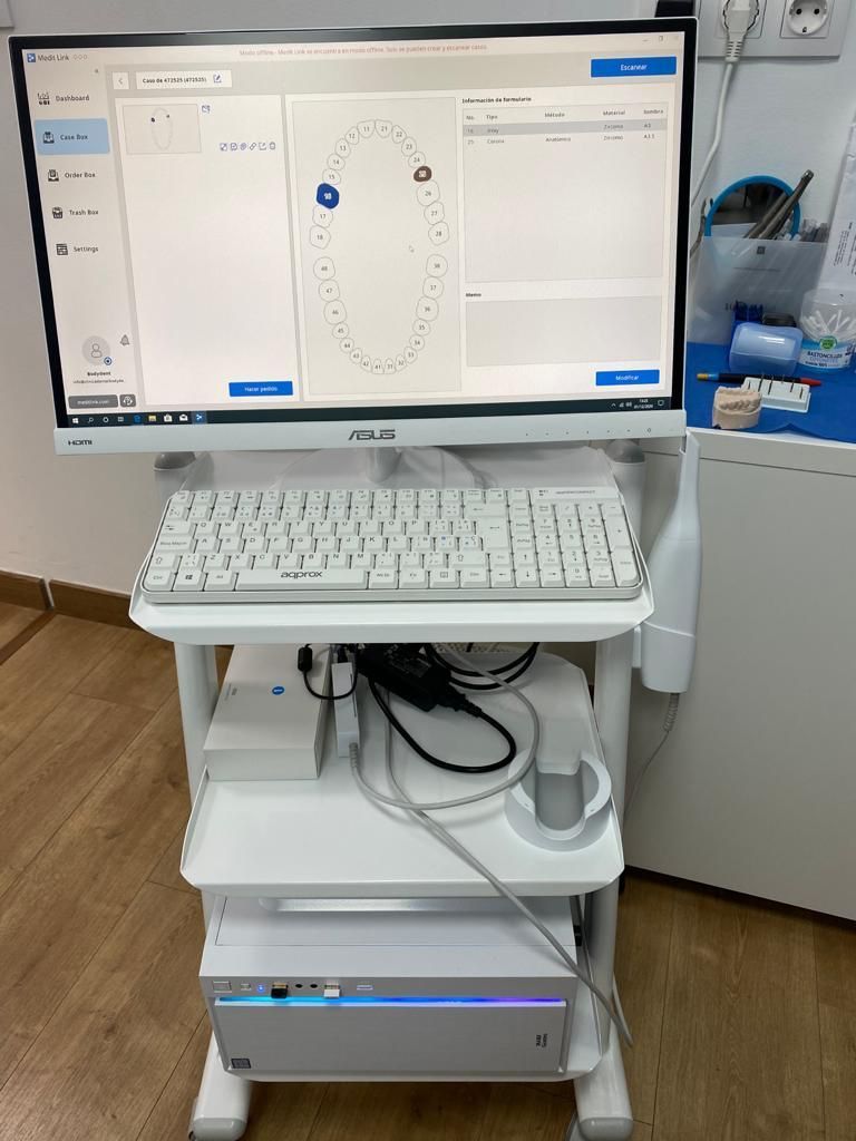 Una computadora está colocada encima de un carrito al lado de un teclado.