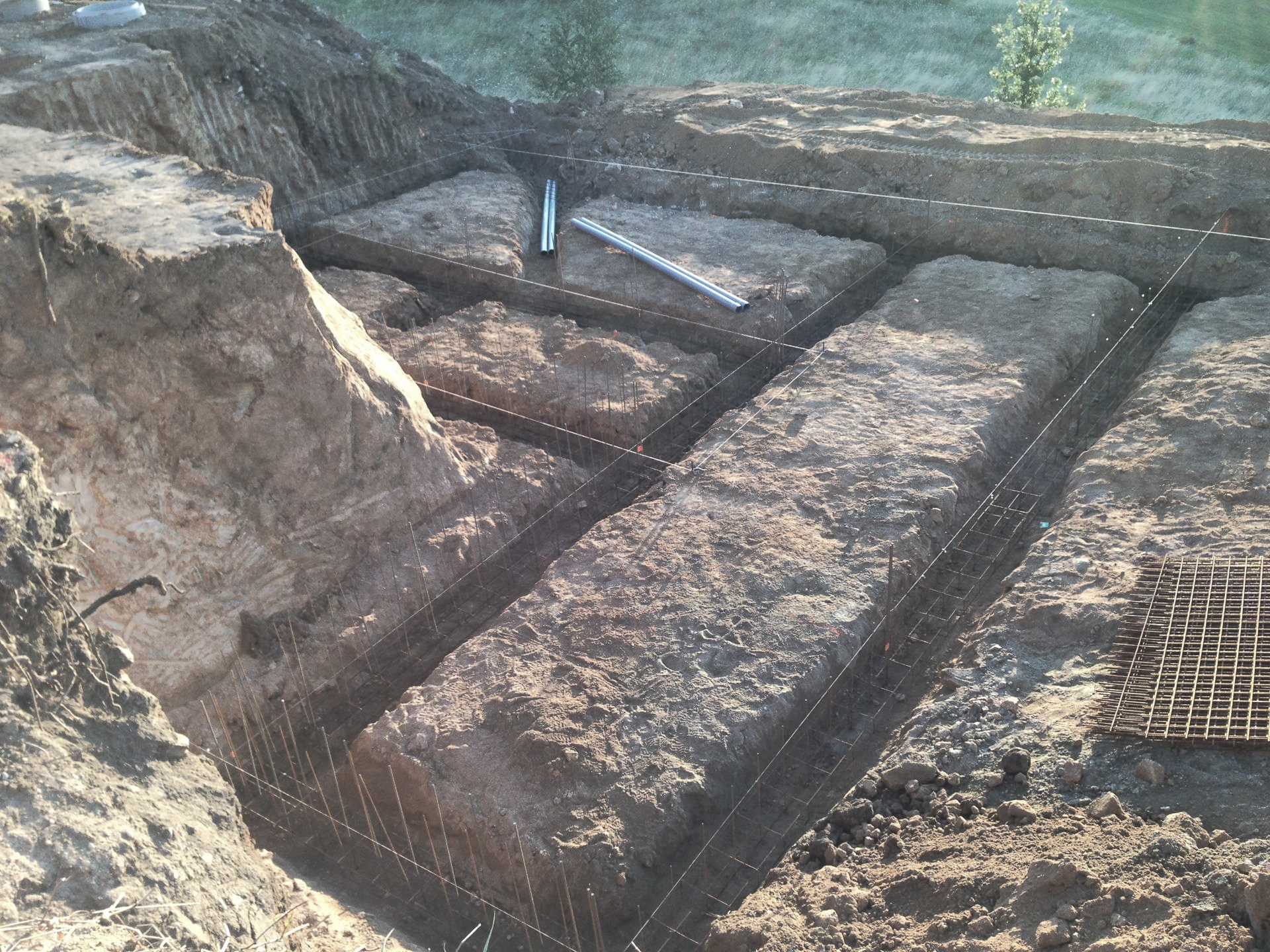 Terrassement pour les fondations d'un bâtiment, montrant les tranchées, les cordes à mine et un niveau dans le sol.