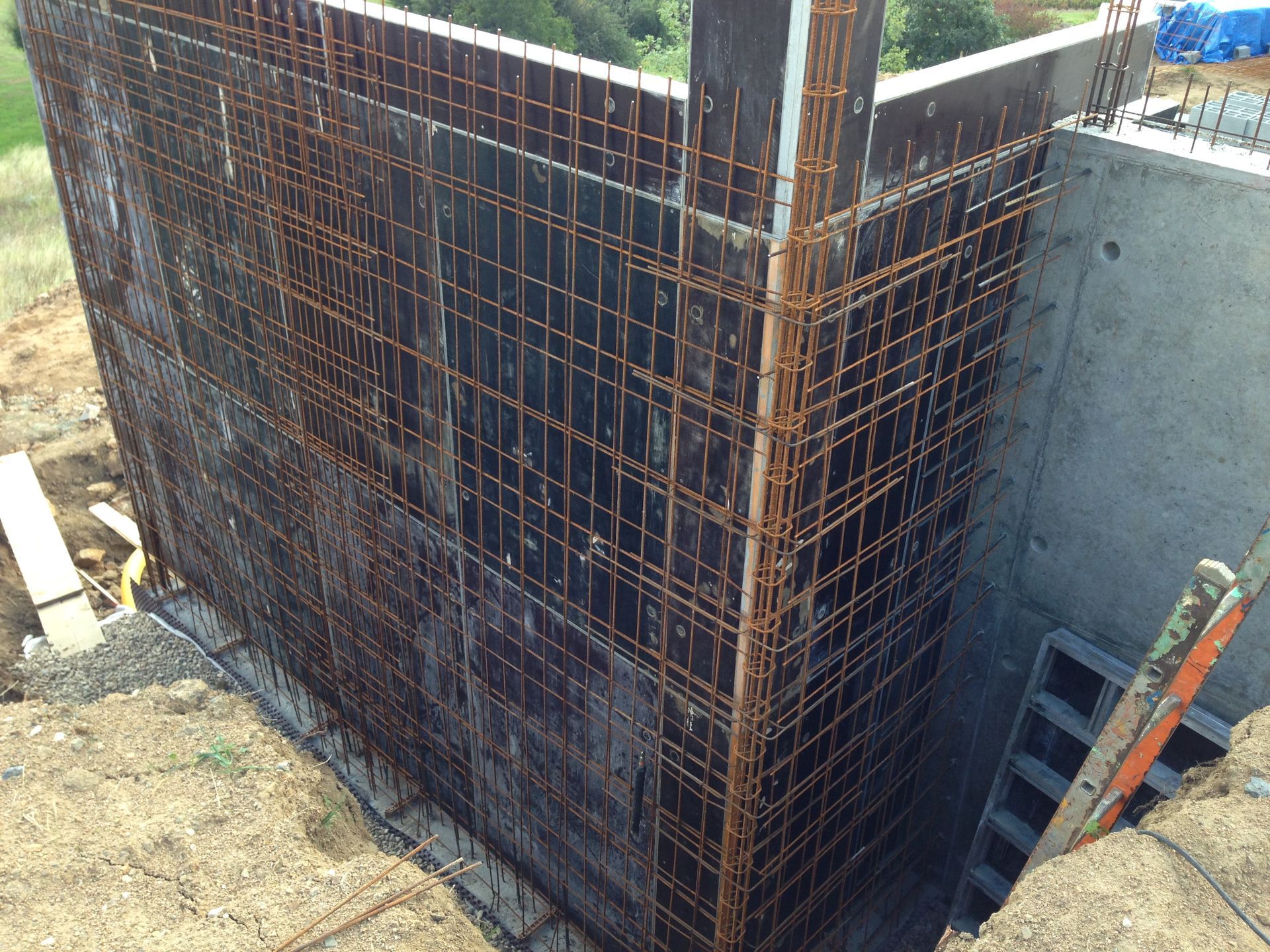 Mur en béton armé en construction ; treillis d'armature contre coffrage en bois.
