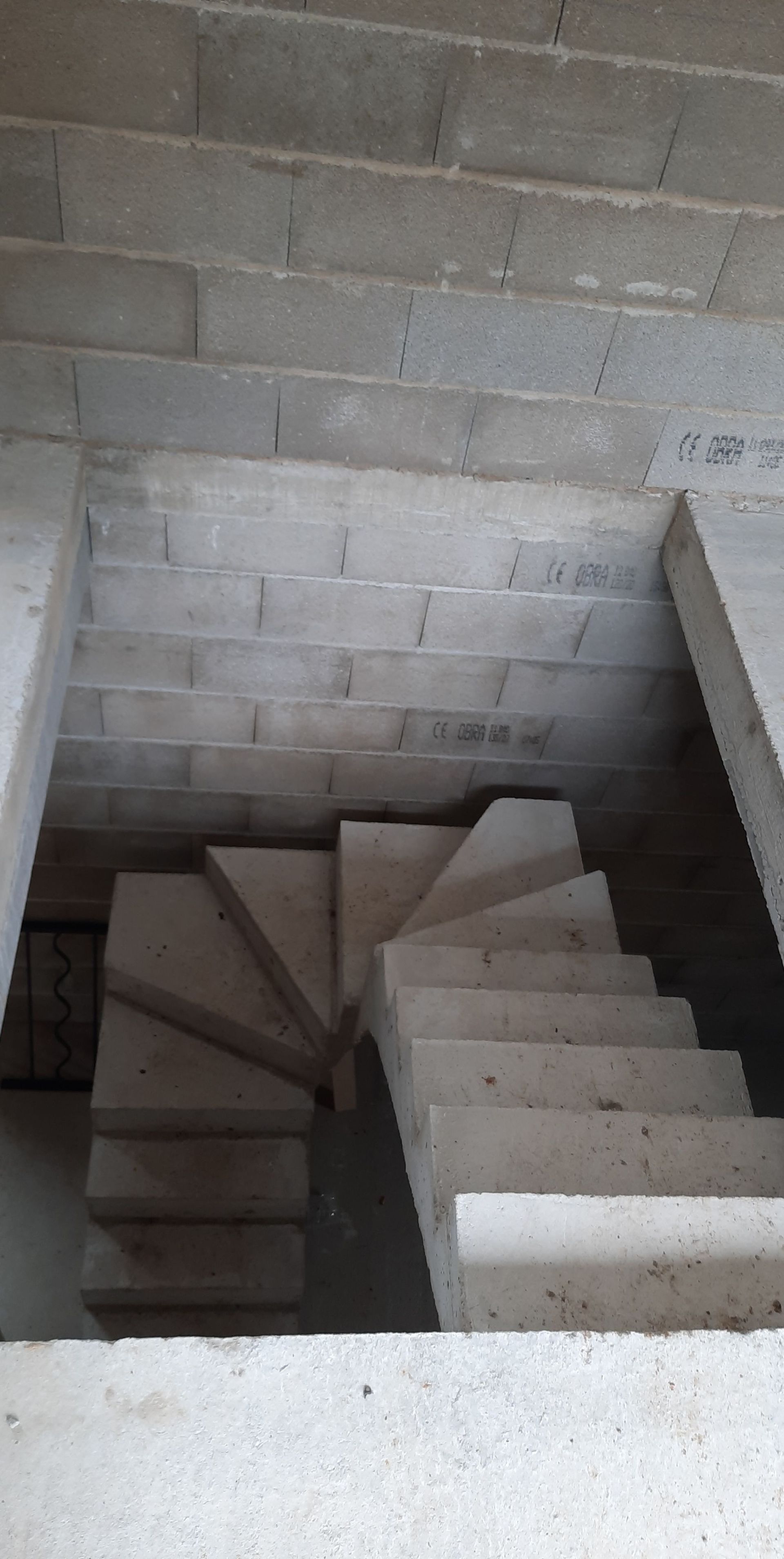 Escalier en colimaçon en béton en construction, encadré par des murs en blocs de béton.