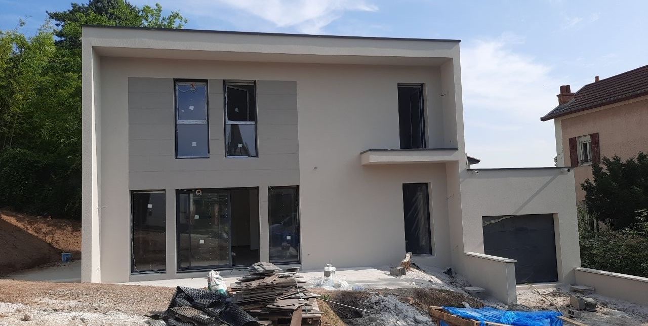 Maison moderne à deux étages avec façade claire, grandes fenêtres et garage attenant en construction.