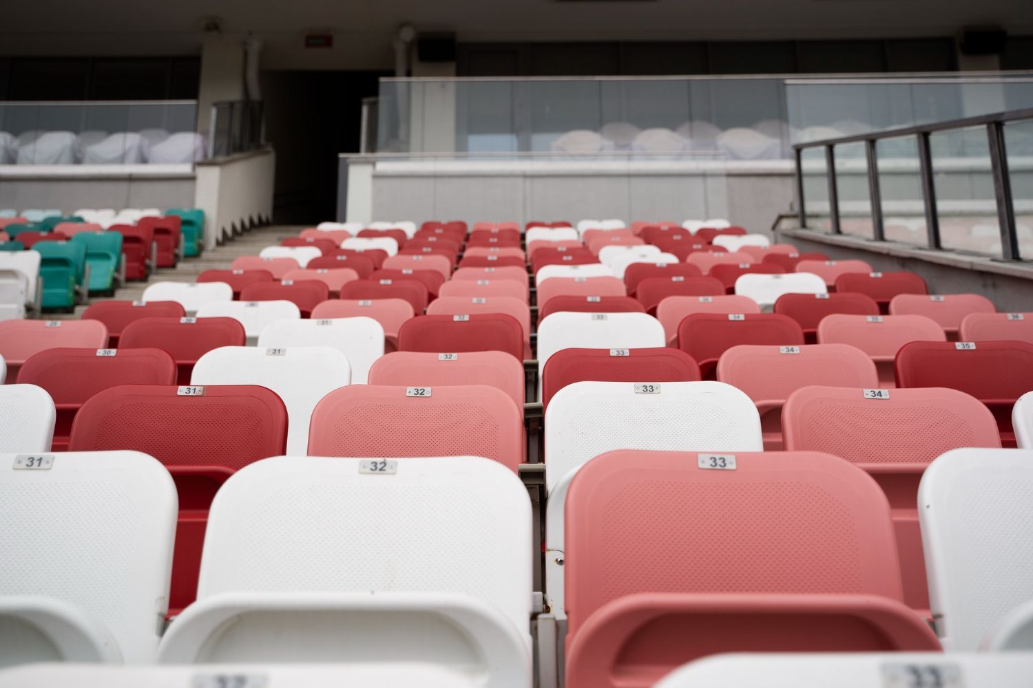 Filas de asientos vacíos del estadio en rojo y blanco, con vista al interior.