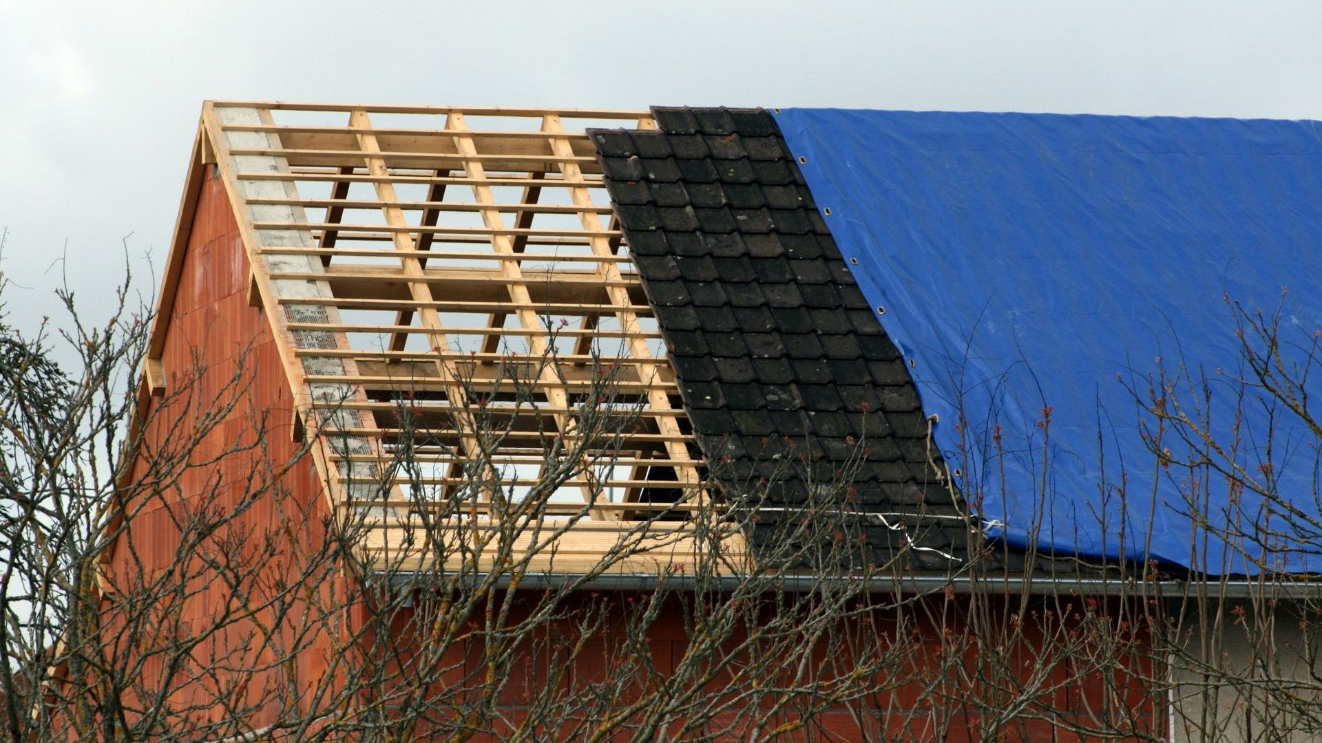 Une bâche bleue sur un toit en rénovation