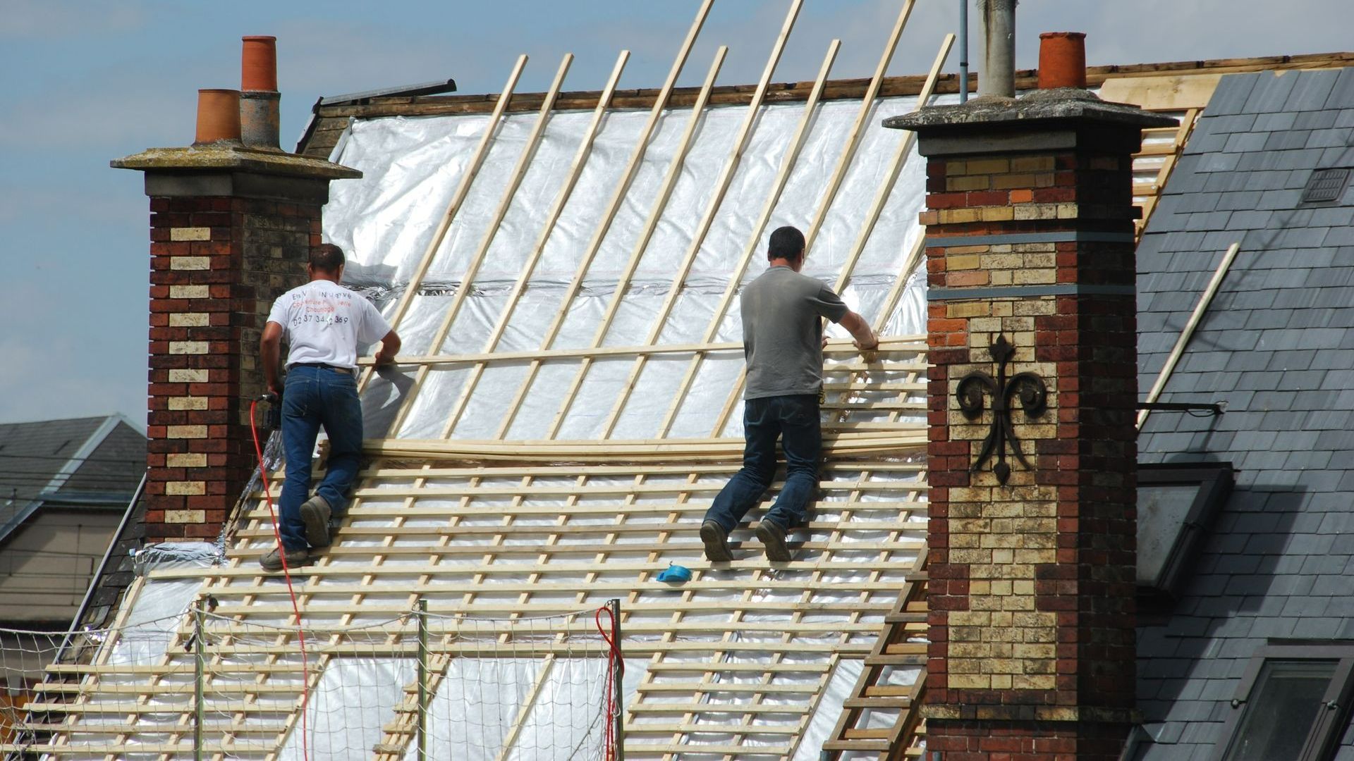 Deux couvreurs isolant un toit