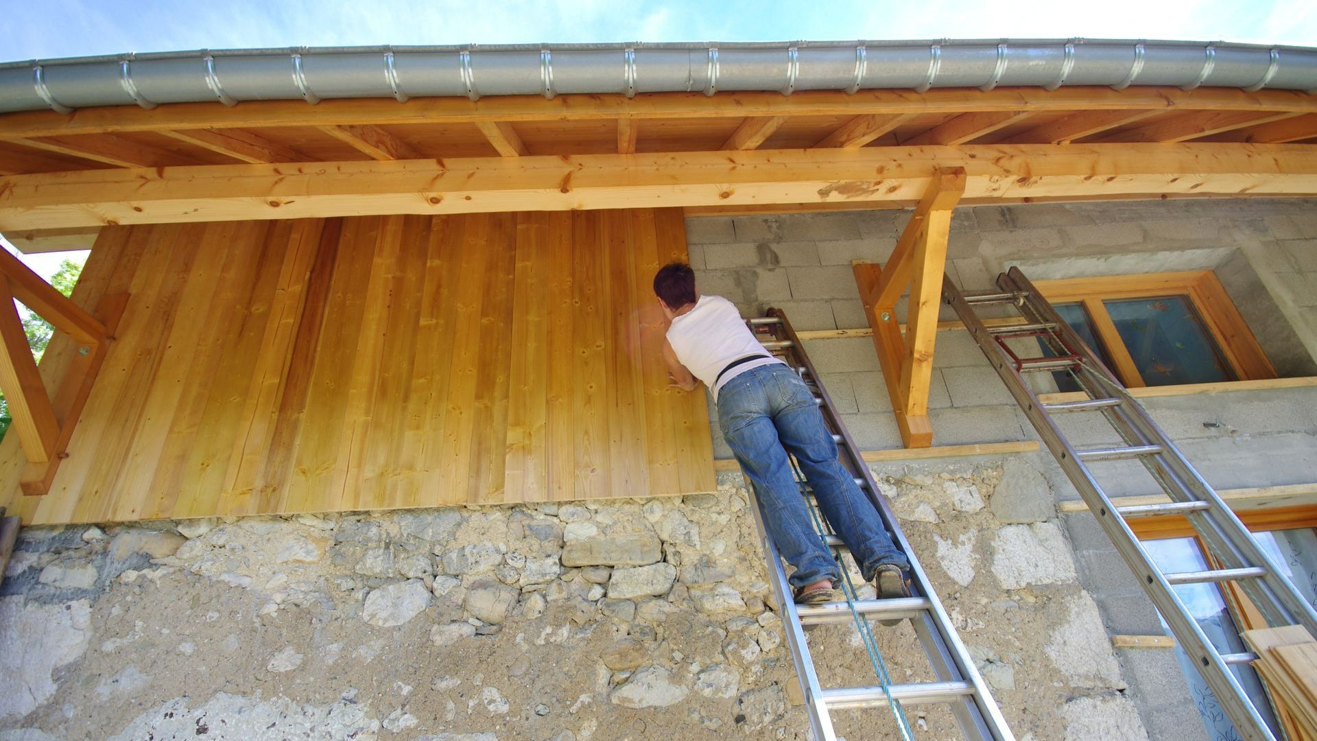 Un artisan couvreur qui pose un bardage en bois sur une façade