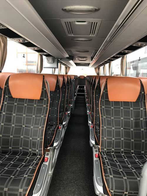 Ein silberner und roter Bus steht auf einem Parkplatz.