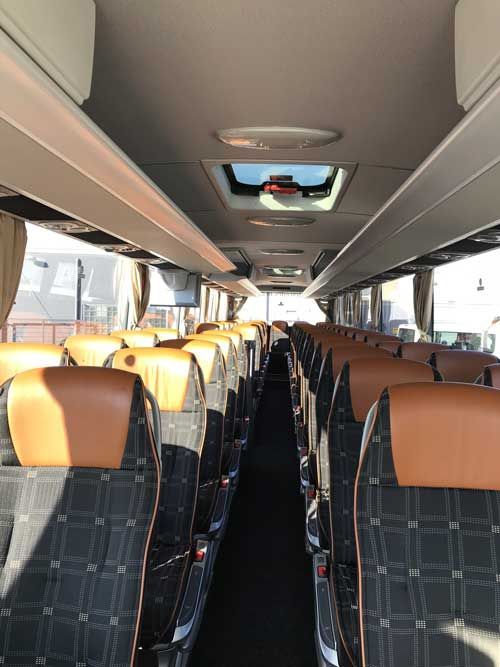 Ein großer silberner Bus steht auf einem Parkplatz.