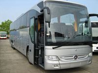 Ein großer silberner Bus steht auf einem Parkplatz.