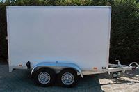 Ein weißer Anhänger steht auf einem Parkplatz.