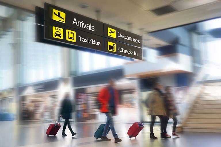 Ein verschwommenes Bild von Menschen, die mit Gepäck durch einen Flughafen gehen.