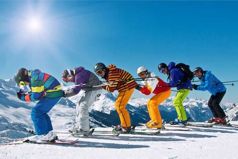 Eine Gruppe von Leuten fährt einen schneebedeckten Hang hinunter.