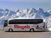 Ein Mingels-Bus parkt vor schneebedeckten Bergen.