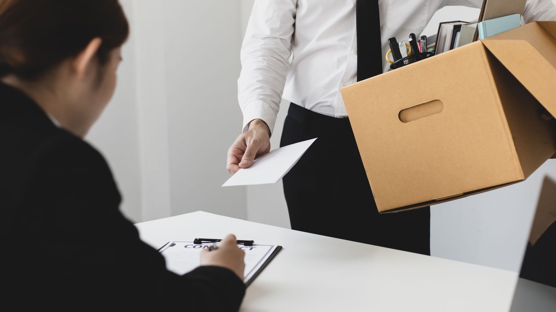 Homme avec un carton qui pose une lettre sur le bureau de sa supérieure
