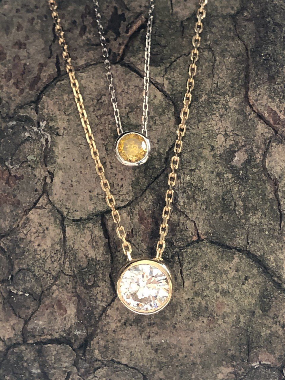 Colliers Diamants : une version Diamant Fancy Yellow naturel, monté en serti clos sur une chaîne en or blanc et une version Diamant Blanc monté sur chaîne en or jaune.