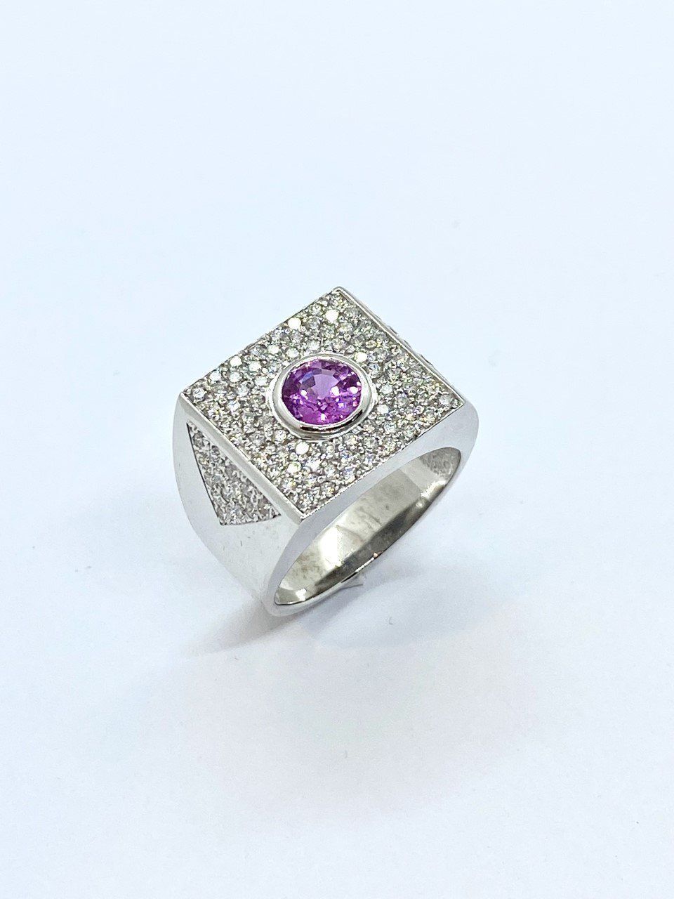 Bague style chevalière en or blanc 750/1000ème pavée de 102 diamants et sertie en son centre d'un saphir rose d'1.10 ct.