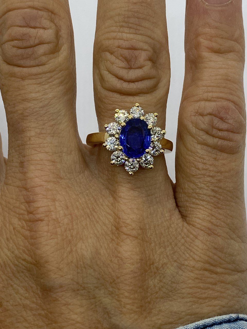 Bague entourage en or jaune 750/1000ème sertie en son centre d'un saphir naturel de 2.10 carats épaulé de 10 diamants.