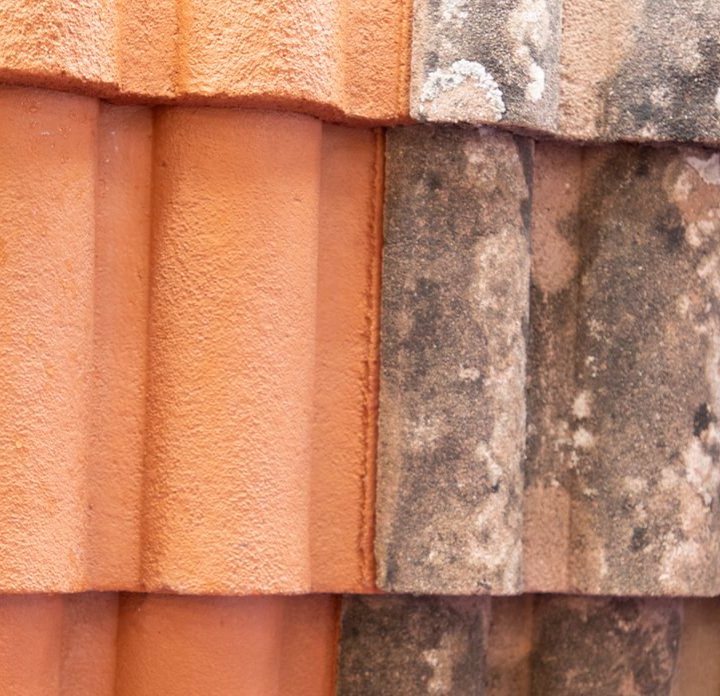 Une toiture avec des tuiles propres et des tuiles recouvertes de mousse