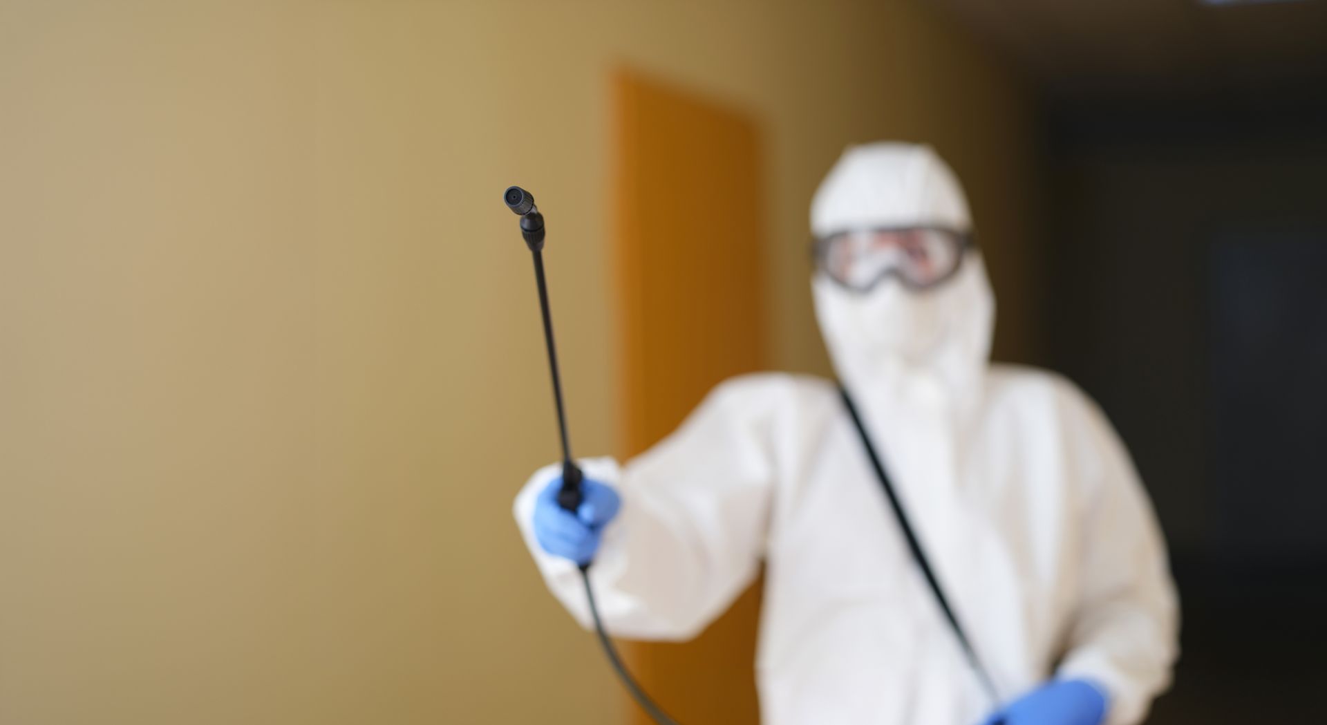 Une personne en combinaison de protection pulvérise du désinfectant dans un couloir.