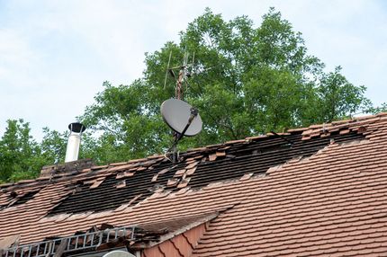 Arbeiter montiert graue Metalldachplatten mit einem Elektrowerkzeug