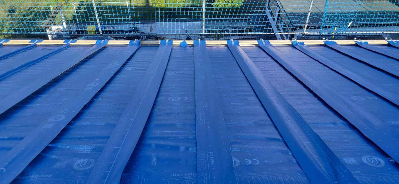 Blaue Metalldachplatten, im Hintergrund ein Stadiontribünenbereich
