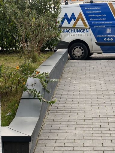 Arbeiter verlegt rote Dachziegel auf einem Hausdach unter bewölktem Himmel